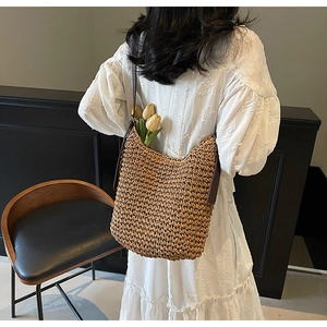 Dettaglio borsa hobo in paglia intrecciata con tracolla in pelle e decorazione di tulipani