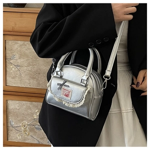 Detail of silver metallic bag with lace trim, gingham bow, and rabbit embroidery