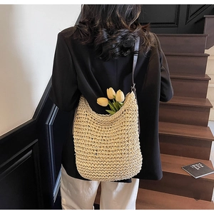 Dettaglio borsa a spalla in paglia intrecciata beige con tracolla in pelle e tulipani
