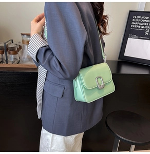 Detail view of mint green glossy leather crossbody bag with silver buckle and shoulder strap