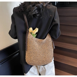 Dettaglio di borsa a spalla in paglia intrecciata con spalline in pelle marrone scuro