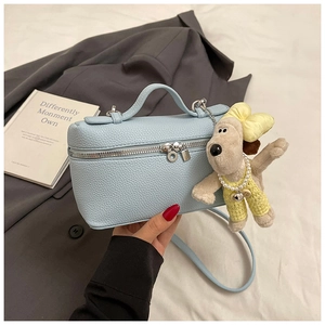 Detail of light blue lychee leather box bag with double zipper and plush dog charm