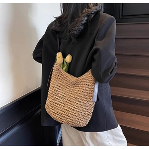 Dettaglio di una grande borsa in paglia con tracolla in pelle marrone e spazio ampio