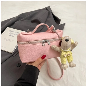 Pink boxy leather bag with pebble texture and cute plush dog pendant charm attached