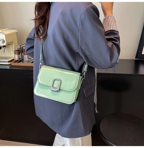 Crossbody shot of a light green square bag with silver metal buckle on a navy blazer