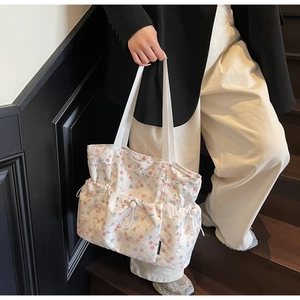 Detail of floral tote bag showing front utility pockets and delicate drawstring design
