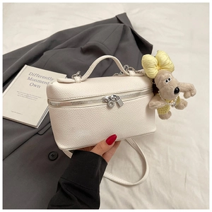 Detail of white lychee leather box bag with silver zippers and plush dog charm
