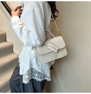 Detail of cream white leather crossbody bag with woven texture and gold metal hardware