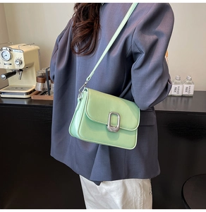 Detail of mint green square crossbody bag with metallic silver buckle on a model