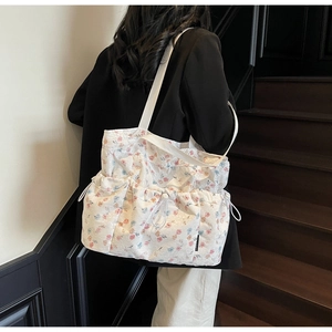Floral canvas tote bag with drawstring pockets shown on a person shoulder strap detail