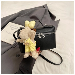 Detail of black lychee grain cylinder bag with silver zipper and cute puppy pendant charm