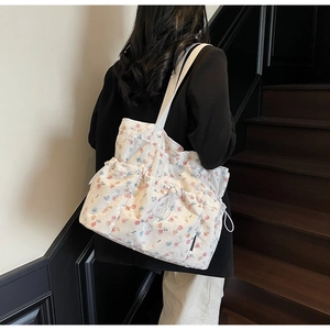 Floral canvas tote bag with drawstring pockets shown on model for size perspective