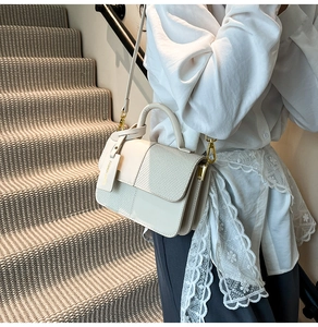 Detail of color-block crossbody bag featuring woven texture and fashion tag detail