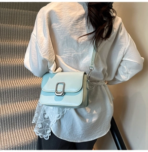Detail of light blue mint square bag featuring a silver lock and adjustable shoulder strap