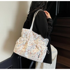 Floral canvas tote bag with drawstring side pockets and jacquard texture on model