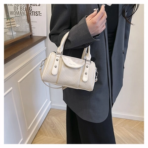 Detail of cream woven texture boston bag with leather handle and silver metal rivets