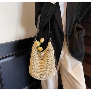 Dettaglio della borsa a tracolla in paglia intrecciata beige con cinturino in pelle marrone