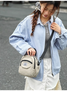 Detail of compact beige nylon crossbody bag with adjustable wide strap and zipper pocket