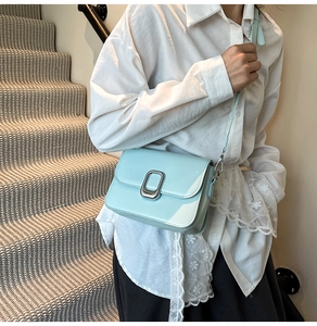 Detail of mint green crossbody bag featuring glossy leather finish and silver metal buckle