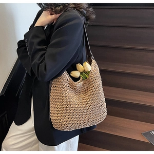 Dettaglio di una borsa tote in paglia con tracolla in pelle e decoro di tulipani