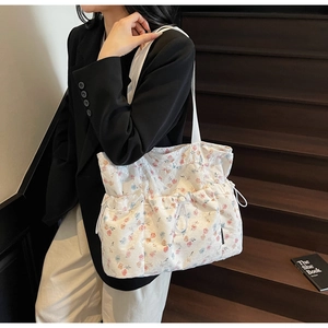 Detail of floral tote bag with drawstring pockets shown on a model on stairs