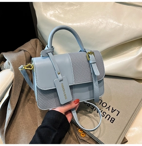 Close-up of a light blue contrast handbag showing leather texture and fashion tag detail