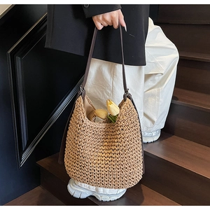 Dettaglio della borsa hobo in paglia intrecciata a mano con spalline marroni e trama rustica