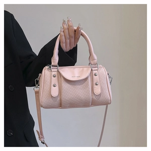 Detail of a pink boston bag with woven texture and adjustable leather shoulder strap