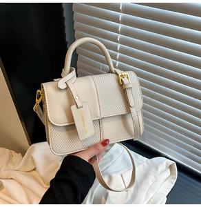 Close-up of contrast color small square bag with textured weaving and golden metal hardware