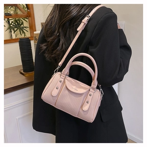 Detail of pink woven leather pillow bag with silver rivets and adjustable shoulder strap