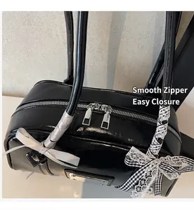 Detail of black patent leather bag featuring smooth dual metal zippers and a ribbon bow