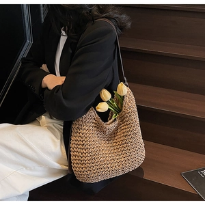 Dettaglio di borsa tote in paglia intrecciata con tracolla marrone e decoro tulipano
