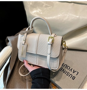 Detail of cream white leather and woven fabric handbag with a matching card holder charm