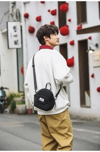 Close-up of black shell-shaped crossbody bag with multi-pocket zipper design on a model