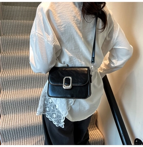 Detail of vintage black square crossbody bag with silver buckle and leather texture