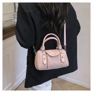 Close-up of pink woven Boston bag with polished silver hardware and leather straps