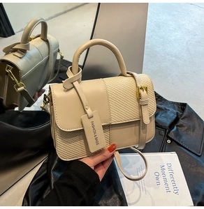 Detail of warm beige handbag featuring woven texture stitching and gold hardware