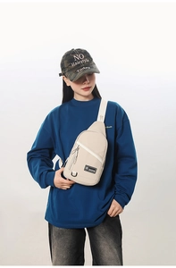 Détail d'un sac bandoulière beige avec sangle réglable et poche zippée frontale