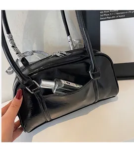 Close-up of black glossy shoulder bag with front pocket and decorative striped bow
