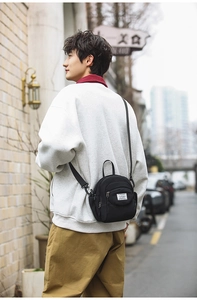 Close-up of a black casual crossbody bag featuring dual zipper pockets and top handle