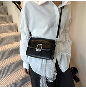 Detail of minimalist black square crossbody bag with elegant silver metallic buckle