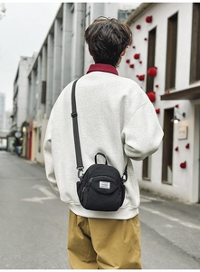 Detailed view of black nylon crossbody bag with adjustable strap worn on the street