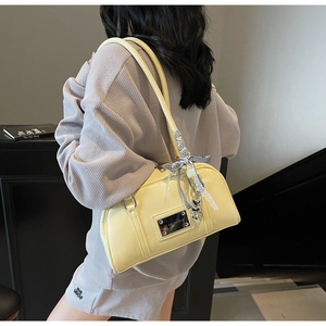 Detail of light yellow pillow bag with glossy finish and ribbon heart charm