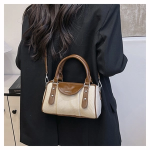 Detail view of woven contrast boston bag with leather straps on a black blazer