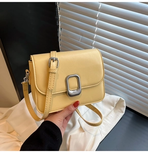 Detail of creamy yellow crossbody square bag with textured PU leather and silver buckle