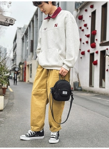 Detail of black utility crossbody bag with multi-layer zippers in a street setting