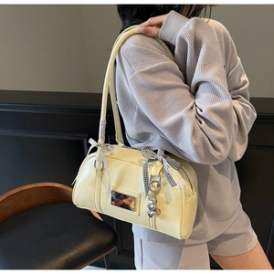 Detail view of butter yellow leather shoulder bag with chic bow and silver heart charm
