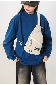 Vue détaillée d'un sac bandoulière en toile beige avec zips et sangle réglable