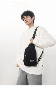 Détail du sac de poitrine en toile noire avec poches zippées et étiquette de marque