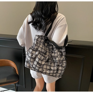 Detail of checkered canvas tote bag featuring functional drawstring side pockets